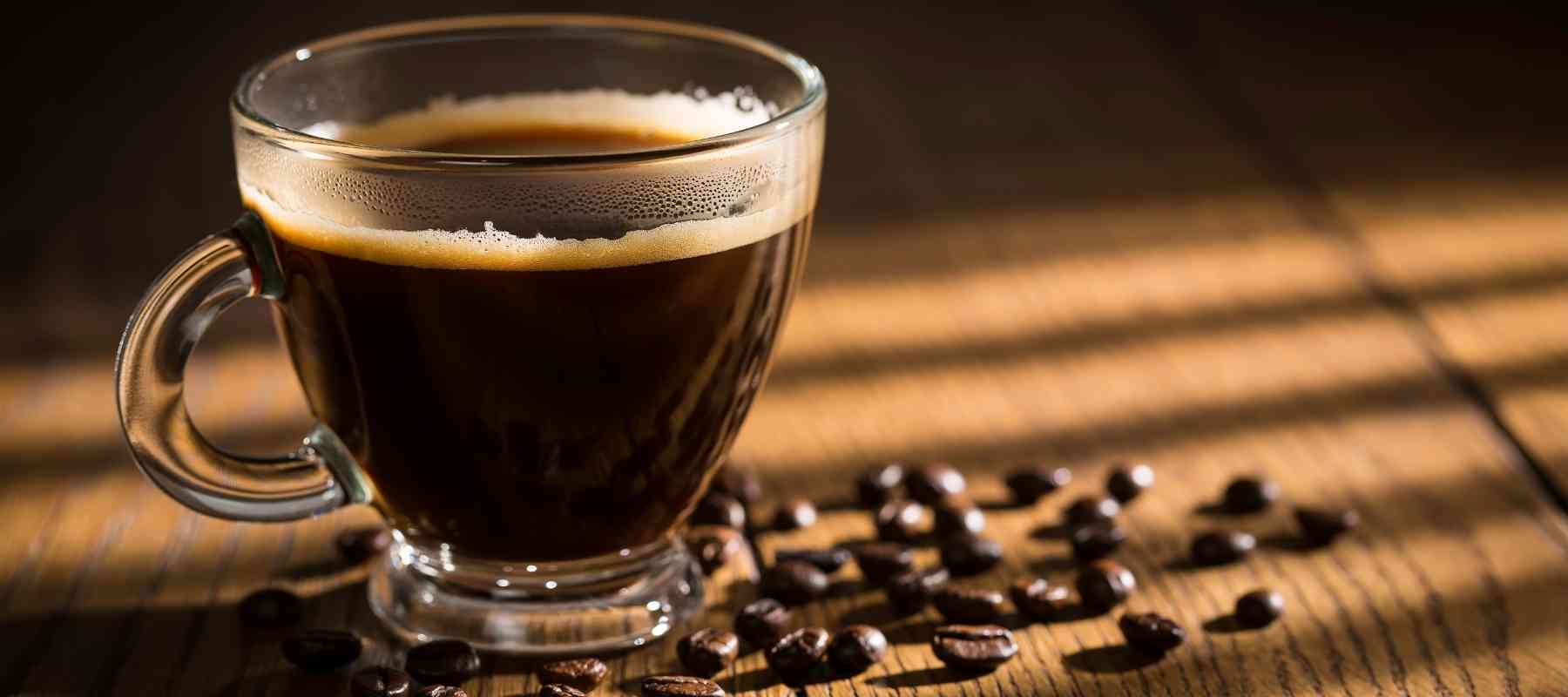 Freshly brewed cup of coffee with coffee beans on wooden table