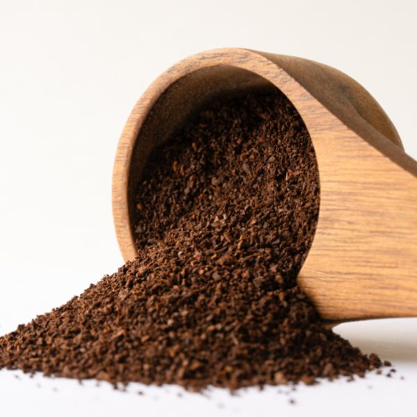 Freshly ground coffee spilling from a wooden scoop, ready to brew