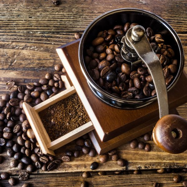 Fresh roasted whole bean coffee with a manual grinder and beans scattered on rustic wood